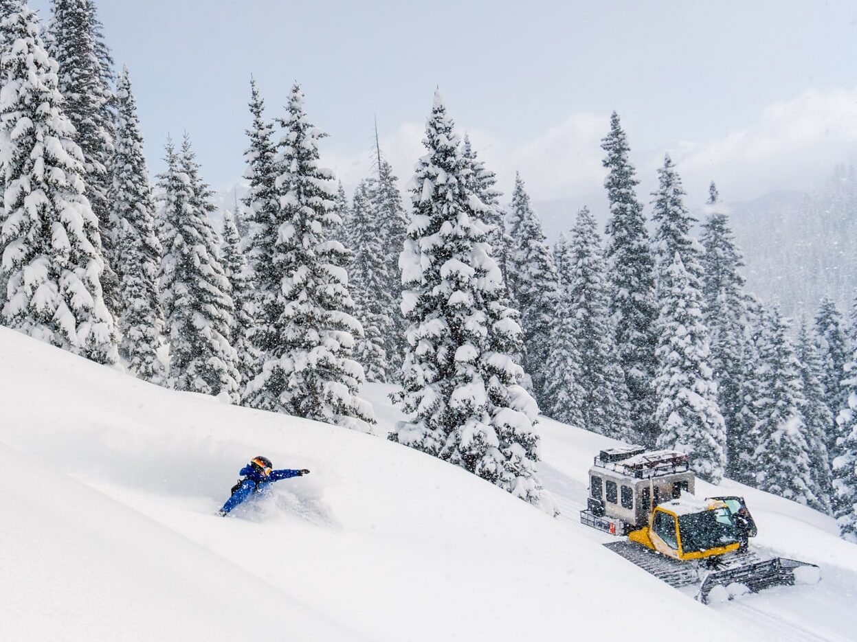 Snowboard takes a deep powder turn on a Purgatory Snowcat Adventures guided backcountry ski trip