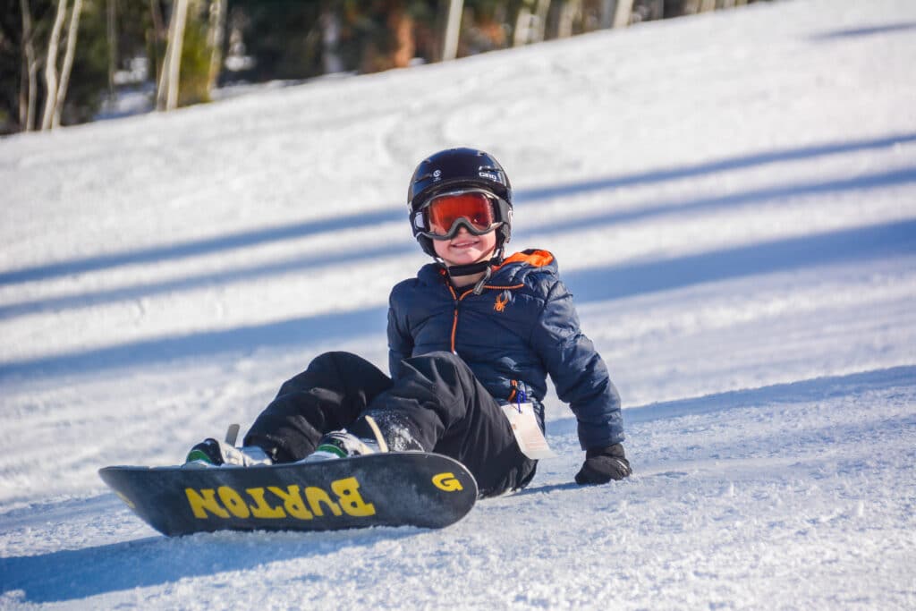 Power Kids snowboarder smiles at the camera during a ski school lesson