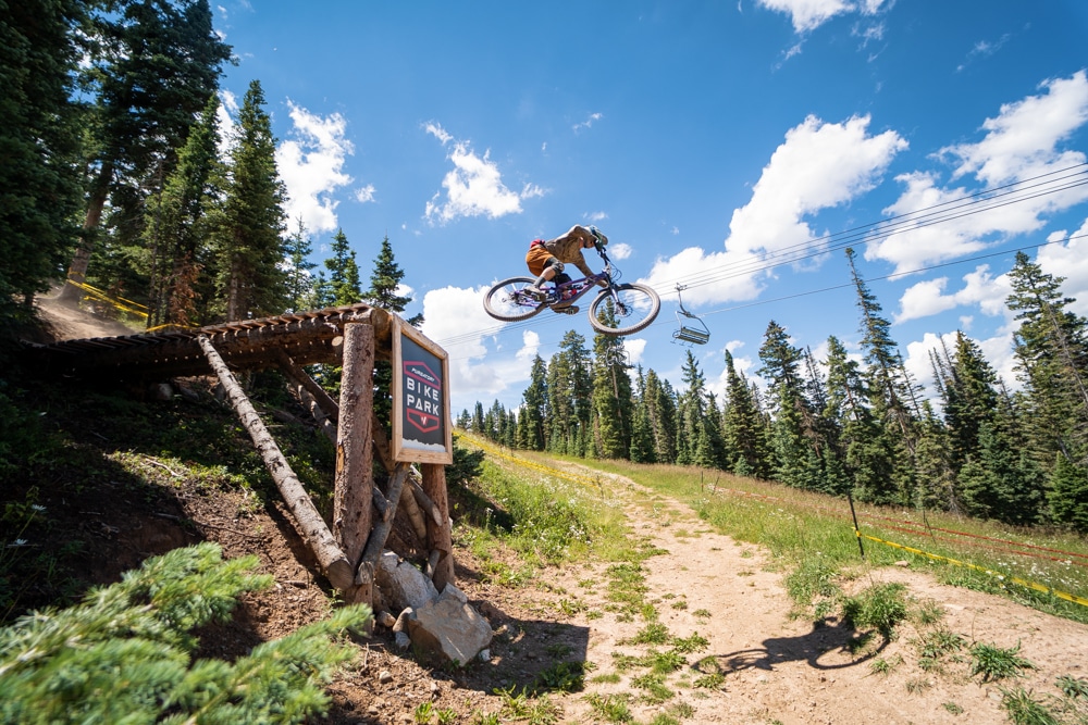 Downhill rider takes on the Purgatory Bike Park road gap jump